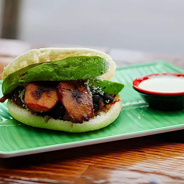 La Arepa's Venezuelan arepa with avocado, plantains, and black beans, served with white sauce.