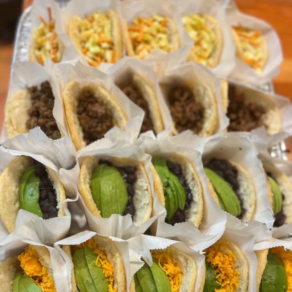 Rows of La Arepa's Venezuelan arepas with various fillings like avocado, black beans, and shredded meat.