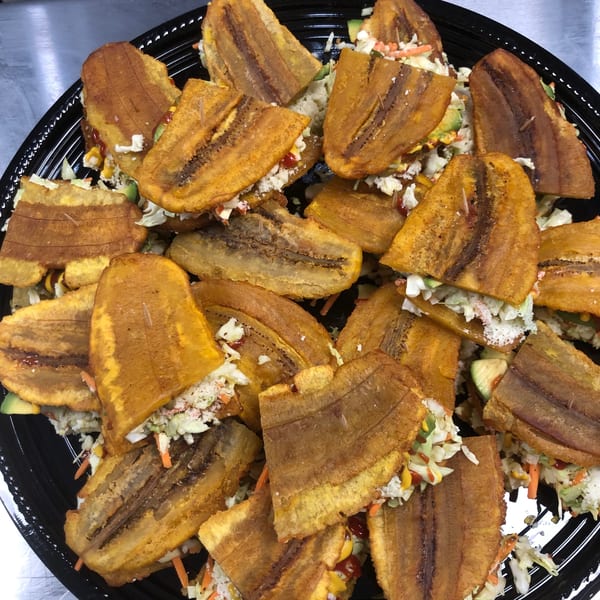 A platter of Venezuelan patacones, fried plantain sandwiches filled with coleslaw, cheese, and sauces.