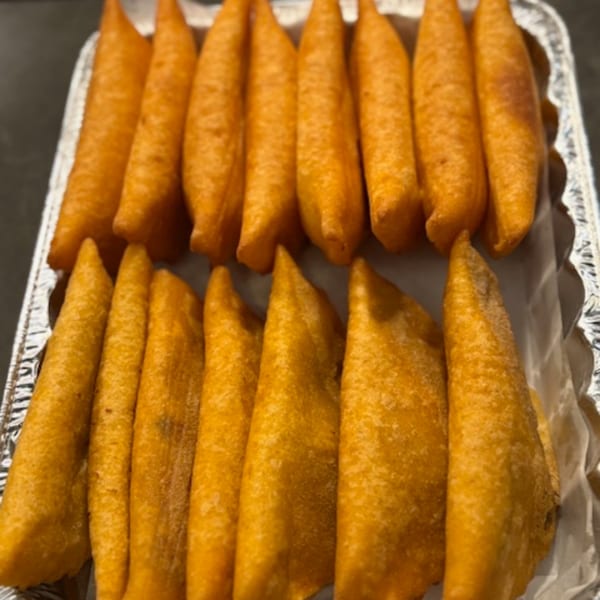 Two rows of golden-fried Venezuelan empanadas, arranged neatly in a foil tray.