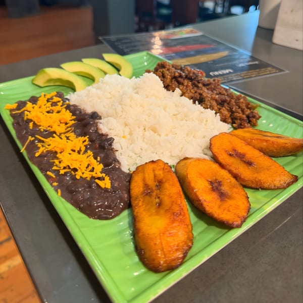 Venezuelan pabellón criollo with rice, black beans, shredded beef, avocado, and fried plantains.