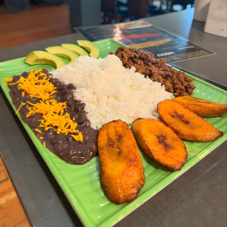 Venezuelan pabellón criollo with rice, black beans, shredded beef, avocado, and fried plantains.