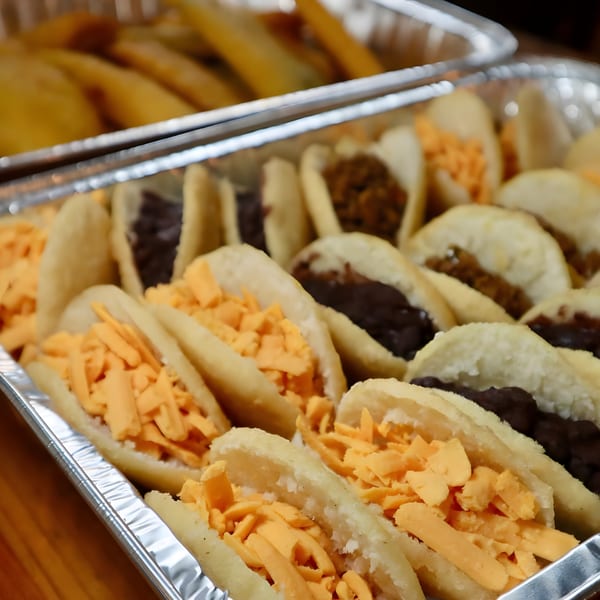 Venezuelan arepas with cheese and black beans in aluminum catering trays.