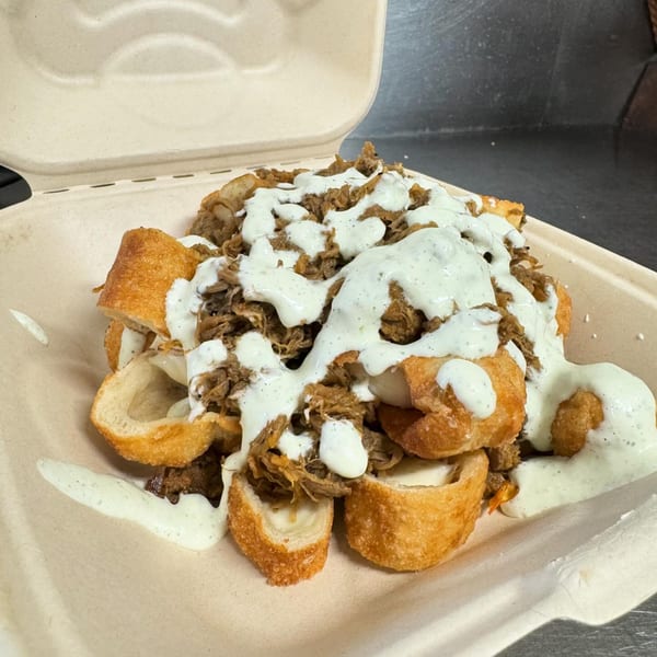 La Arepa's Venezuelan dish features fried dough pieces topped with shredded meat and white sauce.