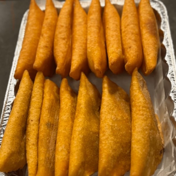 Two rows of golden-brown empanadas, arranged neatly in a silver foil tray.