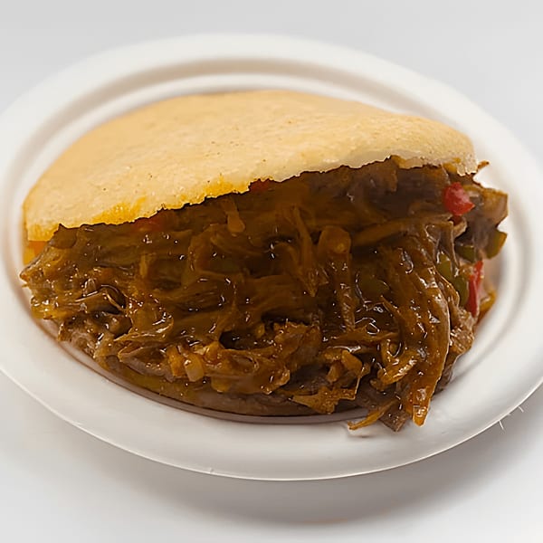 La Arepa's Venezuelan shredded beef and vegetable-filled arepa on a white plate.