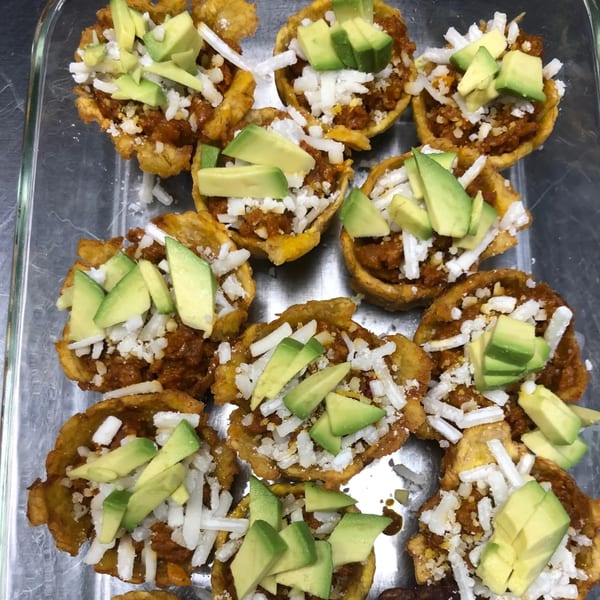 Venezuelan tostones, fried plantain cups filled with meat, shredded cheese, and avocado slices.